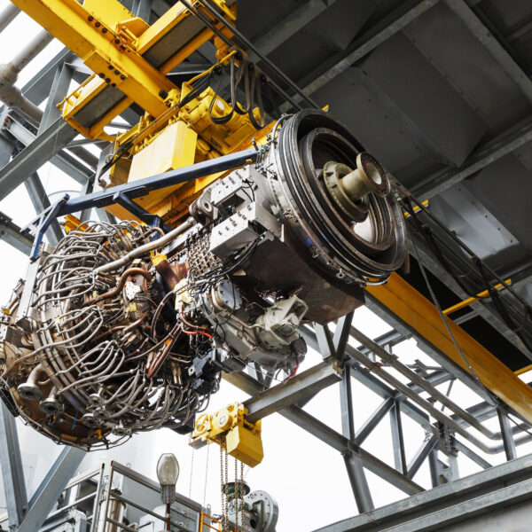 The engine of a gas turbine compressor hangs on a crane during installation in a module for generating electricity